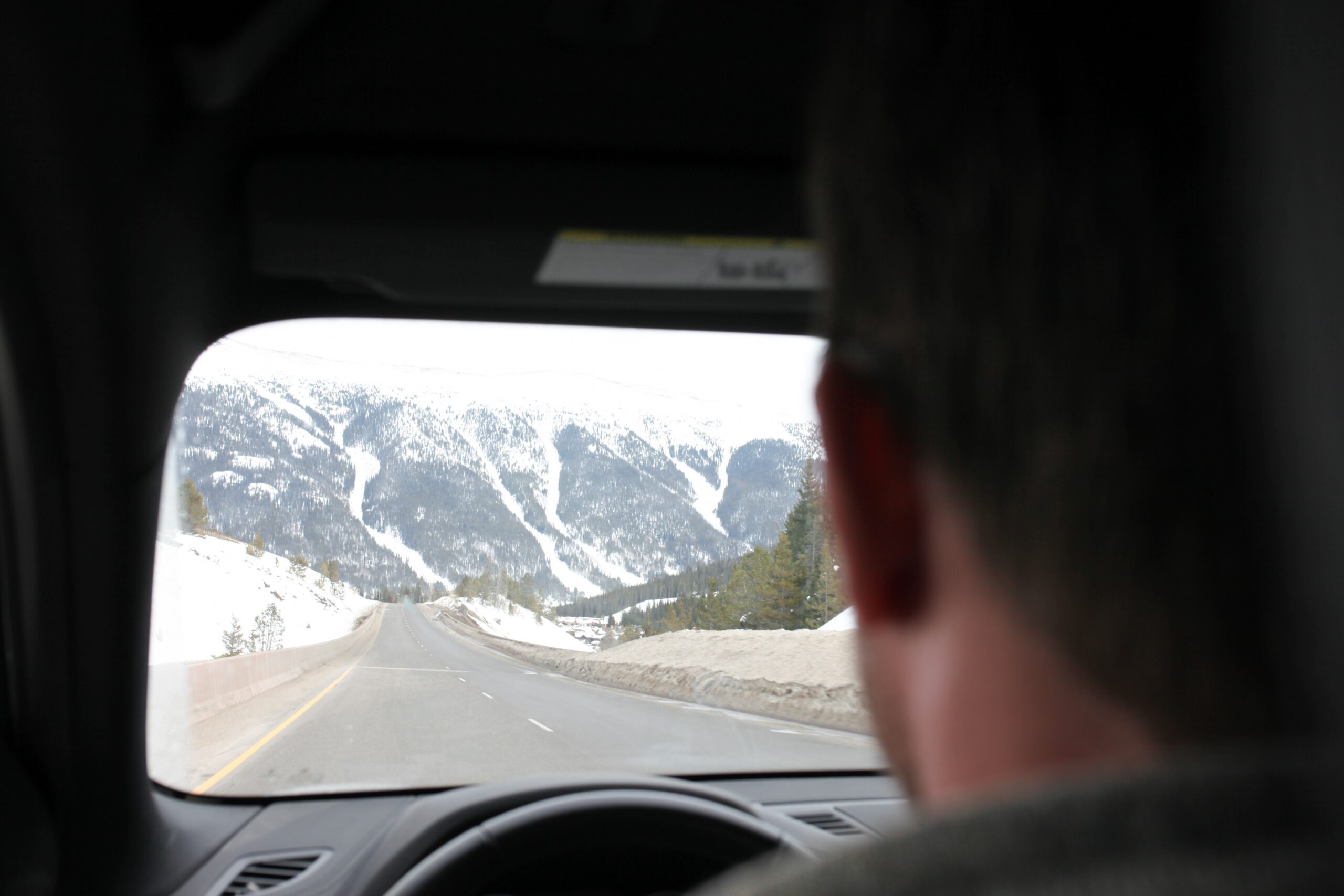 Professional technician repairing a rock chip on a vehicle windshield against a scenic mountain backdrop in Southwest Colorado.